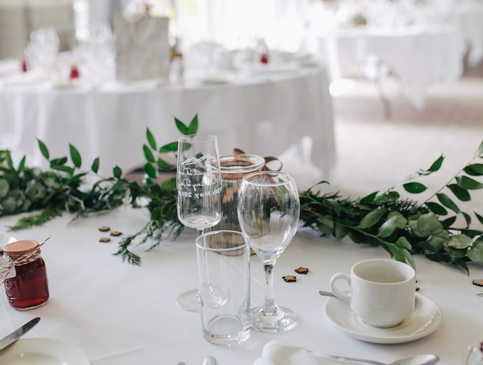 dressage de table pour un accueil officiel avec des couteaux tasse a cafe et soucoupe nappe blanche et plantes vertes