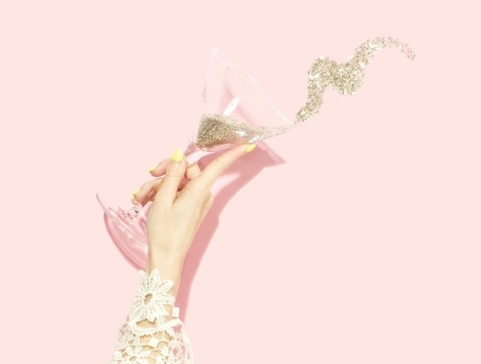 esthetique pastel pop une maine avec manche en broderie et une verre de champagne pleine de pailettes