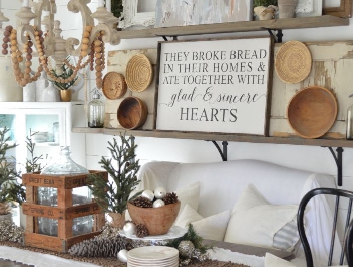 exemple de salon rustique d hiver avec canapé blanc table bois et blanc deco assiettes rotin et bois et des branches de pin lambris mural