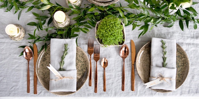 idee de rangement de la table pendant les fetes assiette rouge et des outils cuivres decoration de plantes vertes
