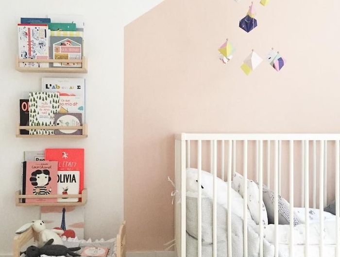 idée déco chambre bébé mur rose pale lit blanc à barreaux parquet bois étagères bois avec des livres enfant exposés