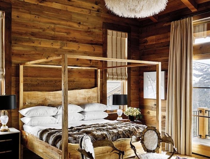 lit baldaquin bois murs et plafond bois brut tabourets bois et fourrure tapis faurroure table touret