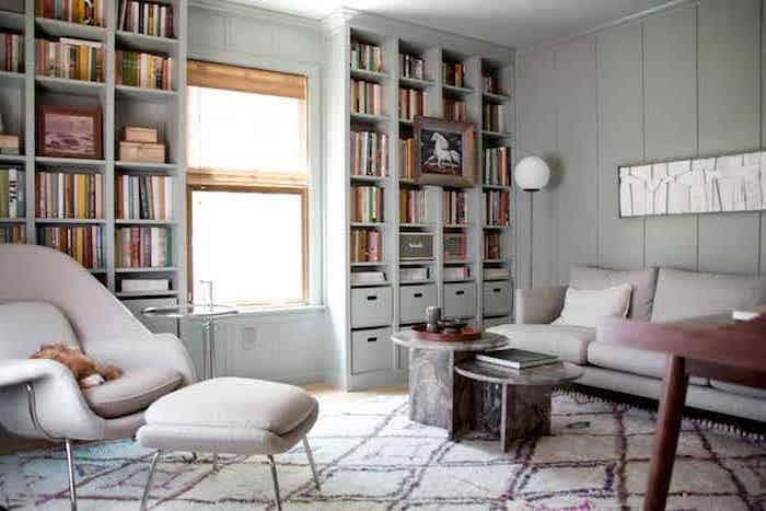 meuble ikea salon deux canapes beiges une fenetre entre deux bibliotheques un tapis en carreax sur le sol