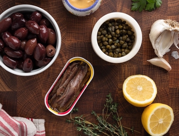 pate a tartiner mediterranee tepanade a la base d olives capres et anchois des produits sur une table nappe en noir et rouge