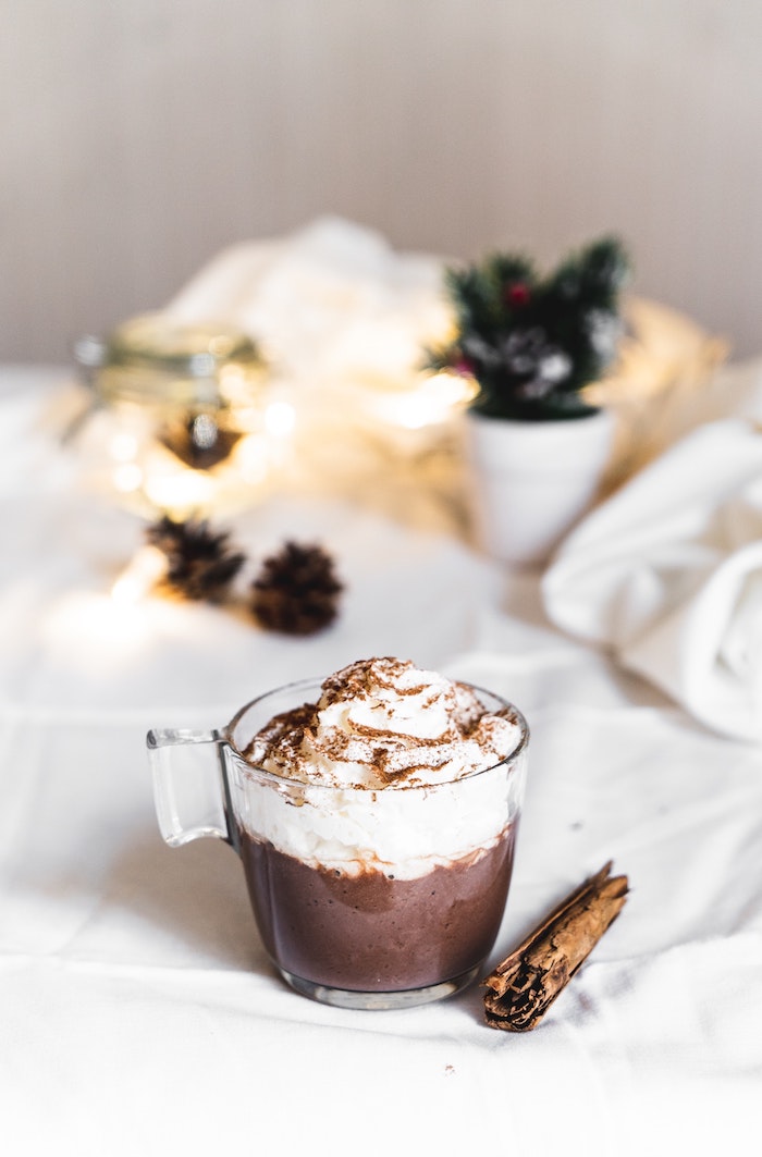 recette chocolat chaud en tasse avec de la crème fouettée et cannelle0sur fond blanc