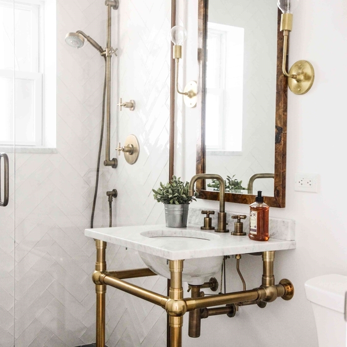 robinet métal évier sur pieds dorés salle de bain vintage revêtement mur carrelage blanc motifs géométriques miroir bois