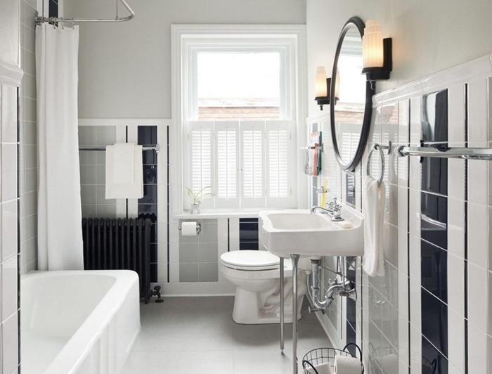 salle de bain style ancien avec baignoire rideaux blancs évier sur pieds métal miroir rond noir carrelage noir