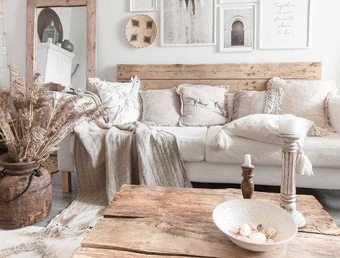 salon blanc et bois avec table basse de bois canapé bois et coussin blanc tapis à franges deco murale de cadres ambiance scandinave