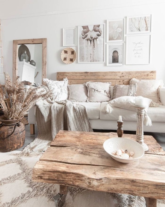 salon blanc et bois avec table basse de bois canapé bois et coussin blanc tapis à franges deco murale de cadres ambiance scandinave