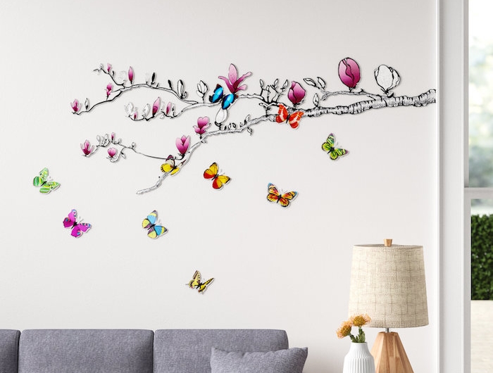 sticker mural dessin branche de mangolia avec des papillons pour la salle de sejour avec un canape gris