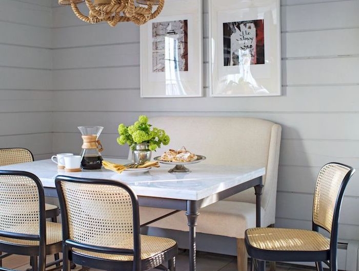 table plan de travail avec des chaises autour et un petit canape en cuir blanc murs et sols en pailles et deux tableaux
