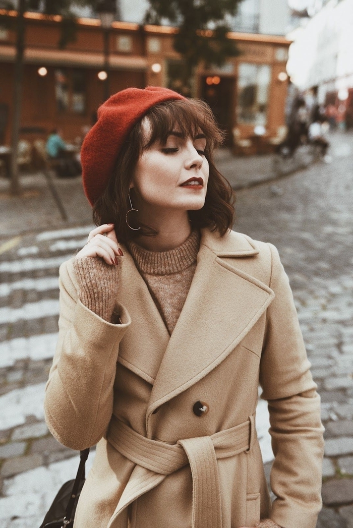 tenue femme hiver béret marron coupe avec frange boucles d oreilles or pull over robe beige manteau ceinture boutons