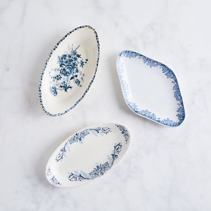 trois assiettes de porcelaine ornamentaux en bleu et blanc poses sur une surface de marbre blanc