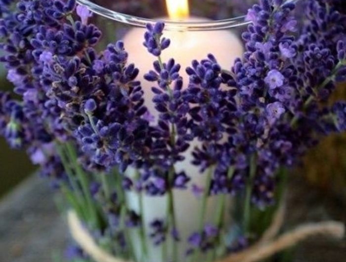 une bougie de lavande dans une verre decoree aux fleurs frais