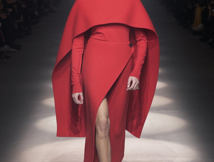 une robe asymetrique rouge kaia gerber sur le podium avec des sandales fines tenue chic femme