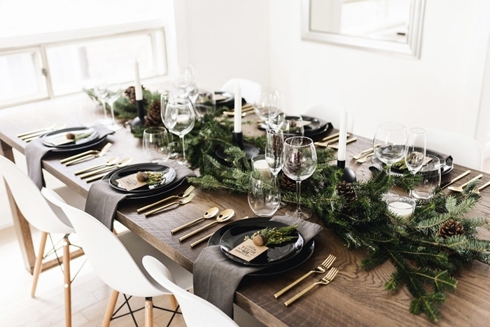 assiette ronde noire serviette noire couvercles or table bois décoration de table de noël branches de sapin bougies