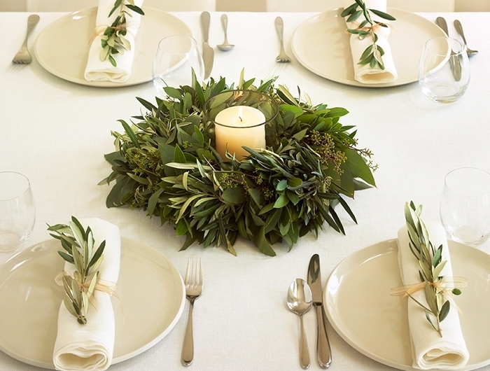 bougie blanche centre de table noel assiette blanche nappe couvercle table argent couronne verdure feuillage