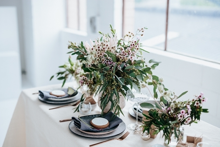 bouquet de plantes vertes herbe assiette ronde blanche serviette noire idee deco table noel couvercles laiton
