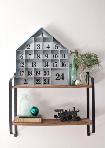 calendrier de l avent ado garcon avec une maison en bois decorative pose sur une etagere