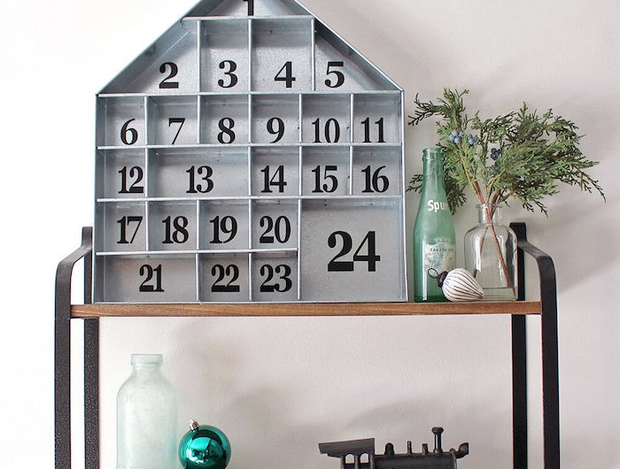 calendrier de l avent ado garcon avec une maison en bois decorative pose sur une etagere