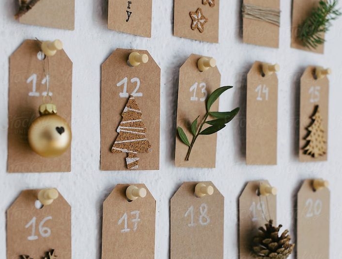 calendrier de l avent original avec des petits notes numerotes decores des petits branches et jouettes papier brun epingle au mur