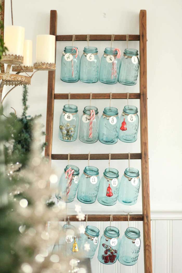 calendrier de l avent original avec des pots suspendus a un escaliers trois bougies blanches et un sapin a cote