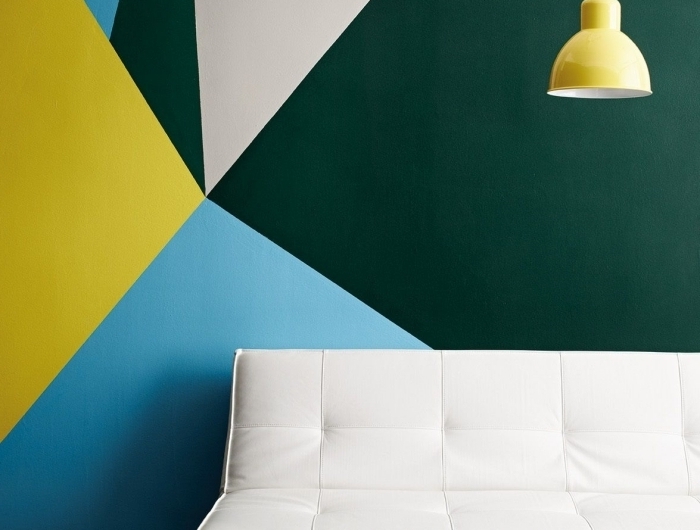 canapé blanc lampe suspendue jaune peinture géométrique mur salon formes triangulaires couleurs peinture vert foncé tendance