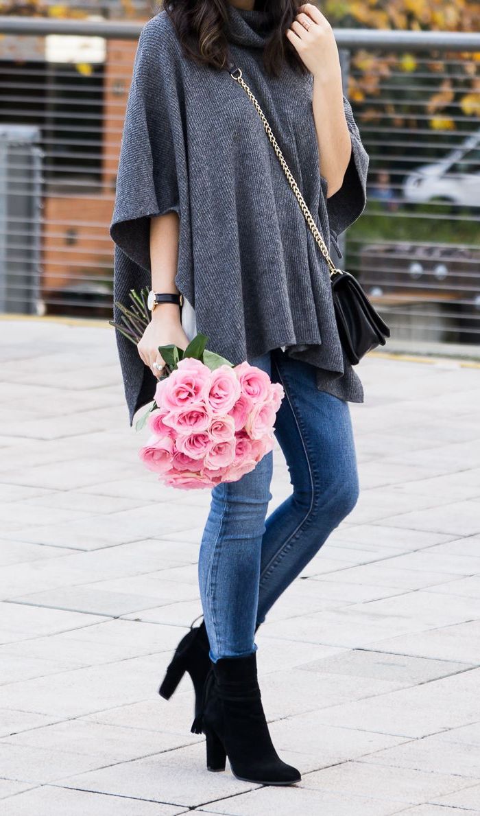 cape fourrure en gris combine avec des jeans et bottes noires une femme qui tient bouquet de roses