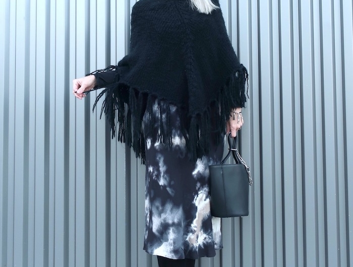 cape noire femme tricotee avec une jupe longue imprimee et sac noir en cuire et bottes en daim