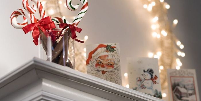 deco cheminée noel avec des cartes festives et des batons en sucre devant une courronne de lumières