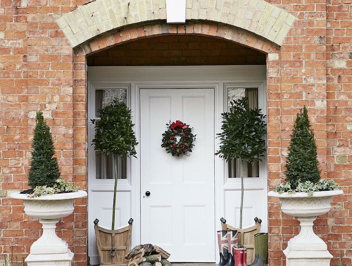 decoration noel exterieure symetrique avec deux arbustes dans des urnes encadrent la porte