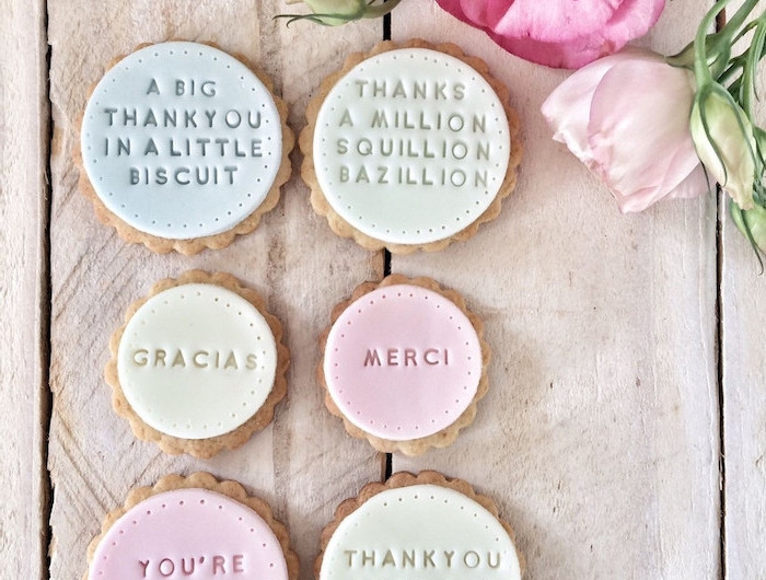 des biscuits personnalisees avec des signatures decores des fleurs sur une table en bois liste cadeau d anniversaire