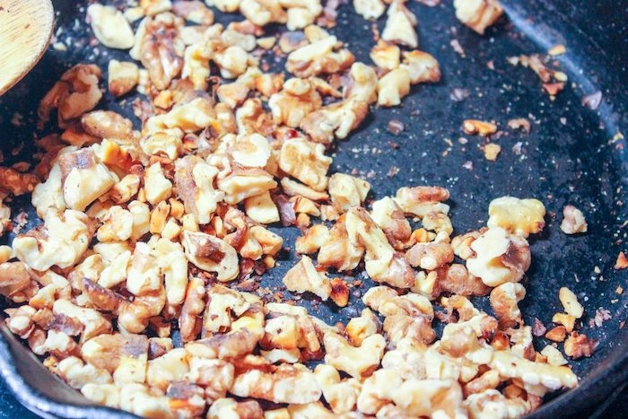 des noix dans une poele portees au feu pour une recette salade d hiver
