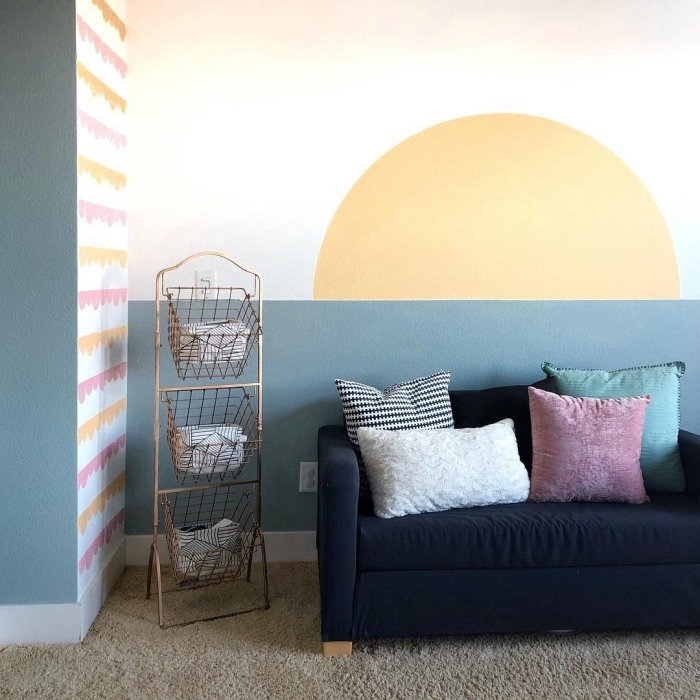 décoration salon mur bicolore idée motif peinture murale canapé noir coussins décoratifs peinture soleil meuble rangement panier