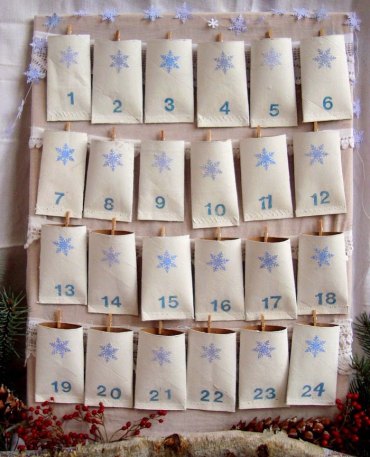 idee calendirer de l avent fait de roouleux de papier de toilette avec des nombres colles sur un panneau avec des plantes de noel