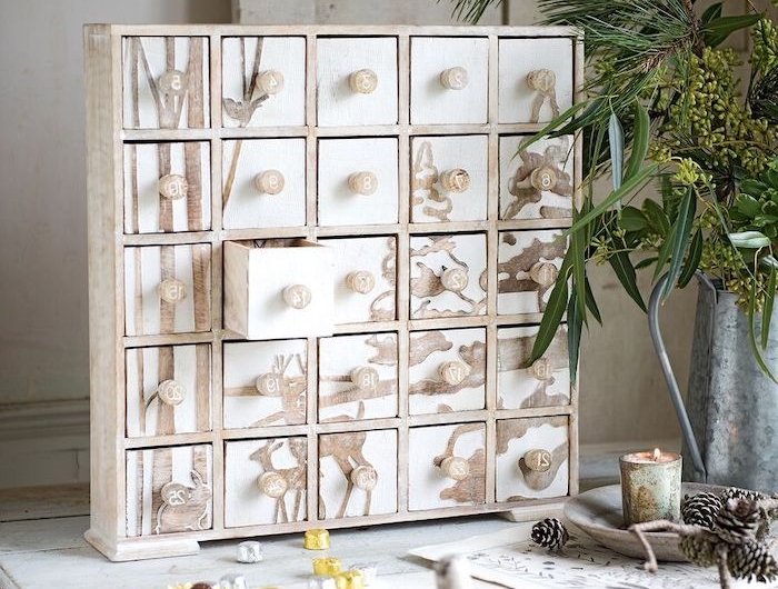 idee calendrier de l avent avec des petites boites en bois pose sur un bureau blanche a cote d une vase a plantes vertes