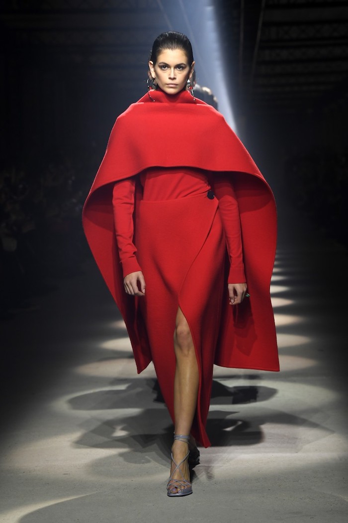 kaia gerber defile avec une cape et une robe rouges tendances automne hiver 2020
