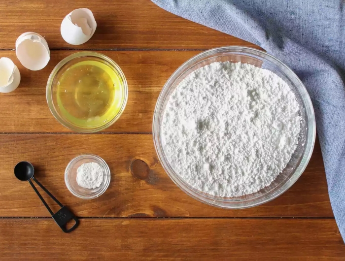 les produits pour un glaçage des oeufs pasteurises un bol de sucre de confeterie avec une nappe sur la table en bois