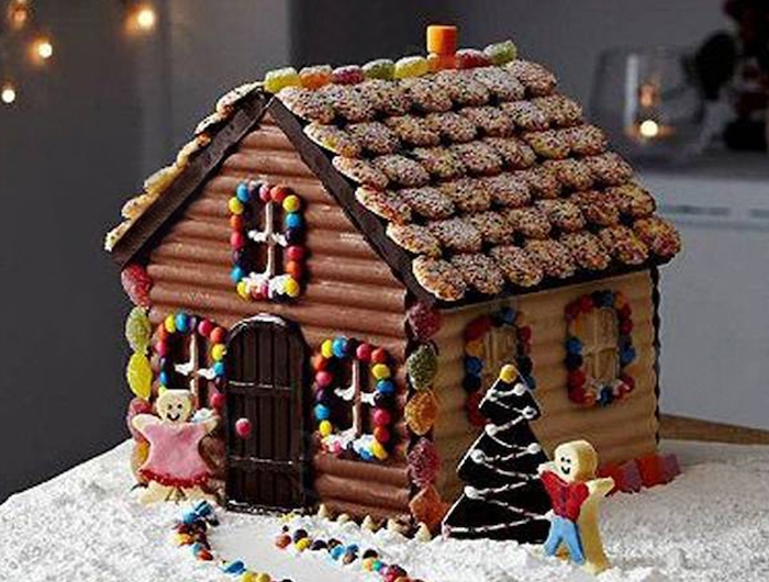 maison en pain d épices décorée avec des petits bonhommes devant la porte et des bonbons gelees sur le toit