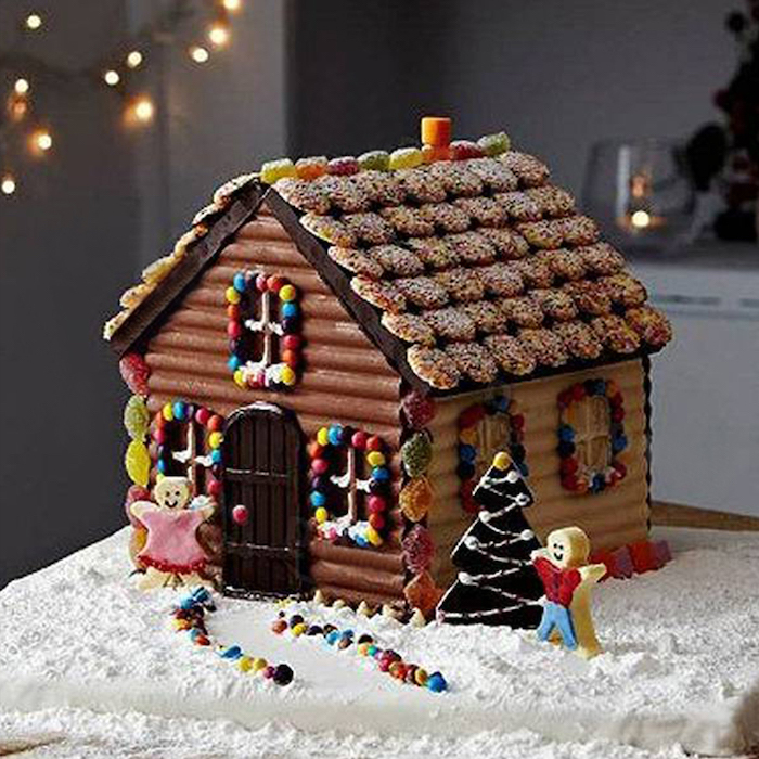 maison en pain d épices décorée avec des petits bonhommes devant la porte et des bonbons gelees sur le toit