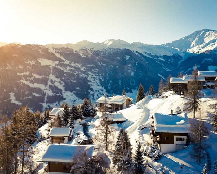paysage montagne hiver rayons soleil sommets montagne enneigée village maison bois toit neige