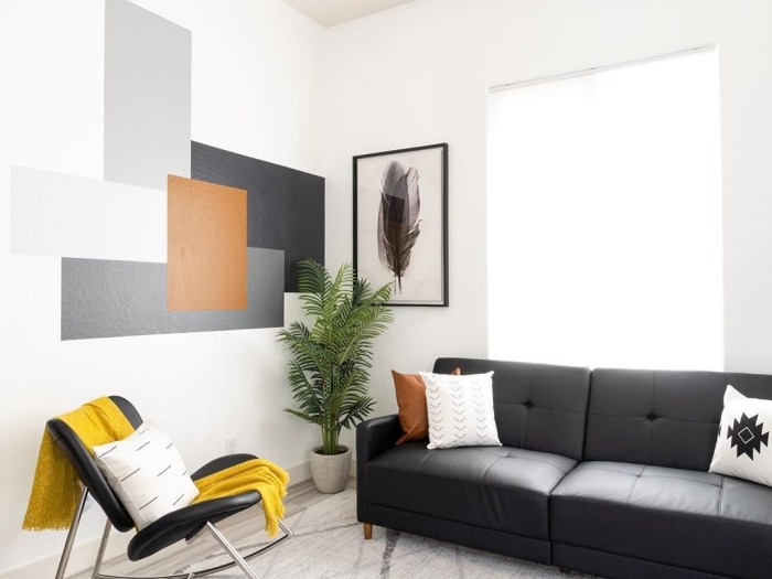peinture géométrique salon décoration moderne aménagement salon canapé boutonné noir coussin blanc chaise noir jeté jaune