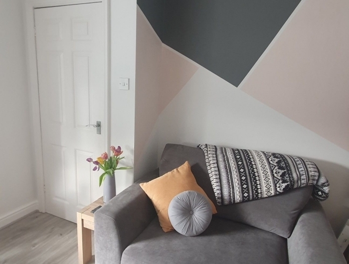 peinture mur triangle fauteuil gris anthracite jeté motifs barbère blanc et noir coussin orange pastel table bois basse