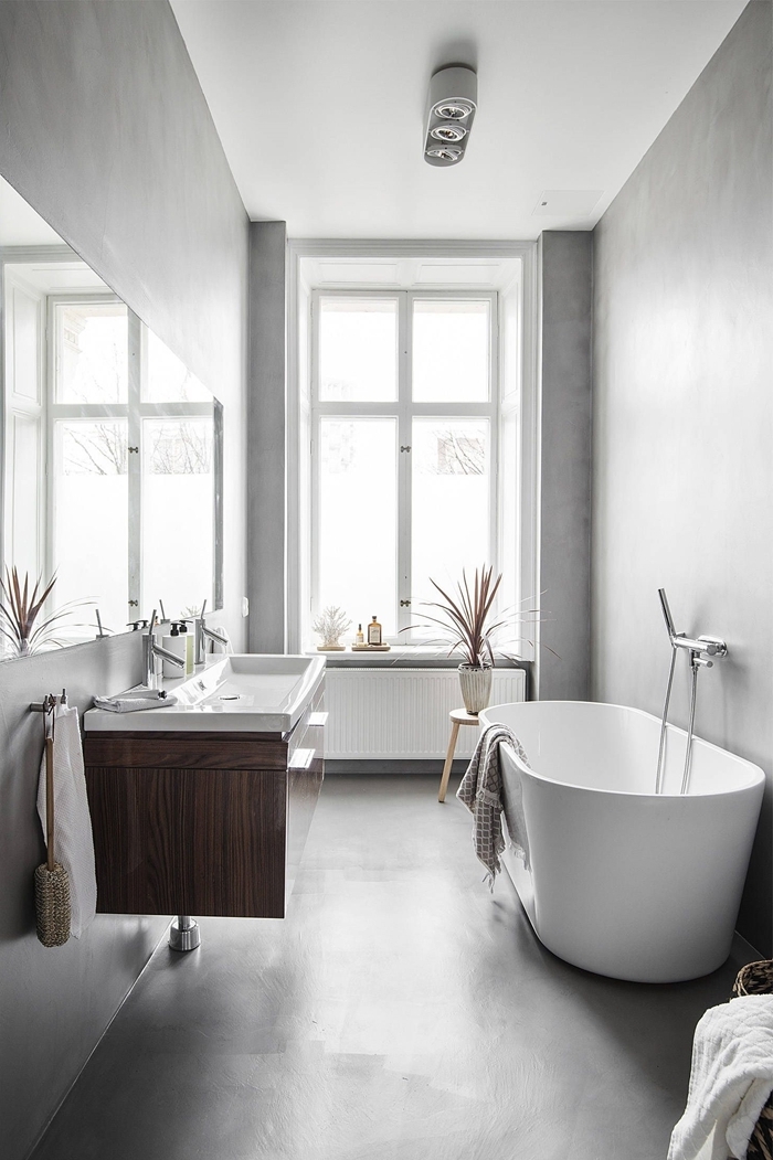 salle de bain avec baignoire blanche autoportante robinet inox table basse cbois plante éclairage spots led