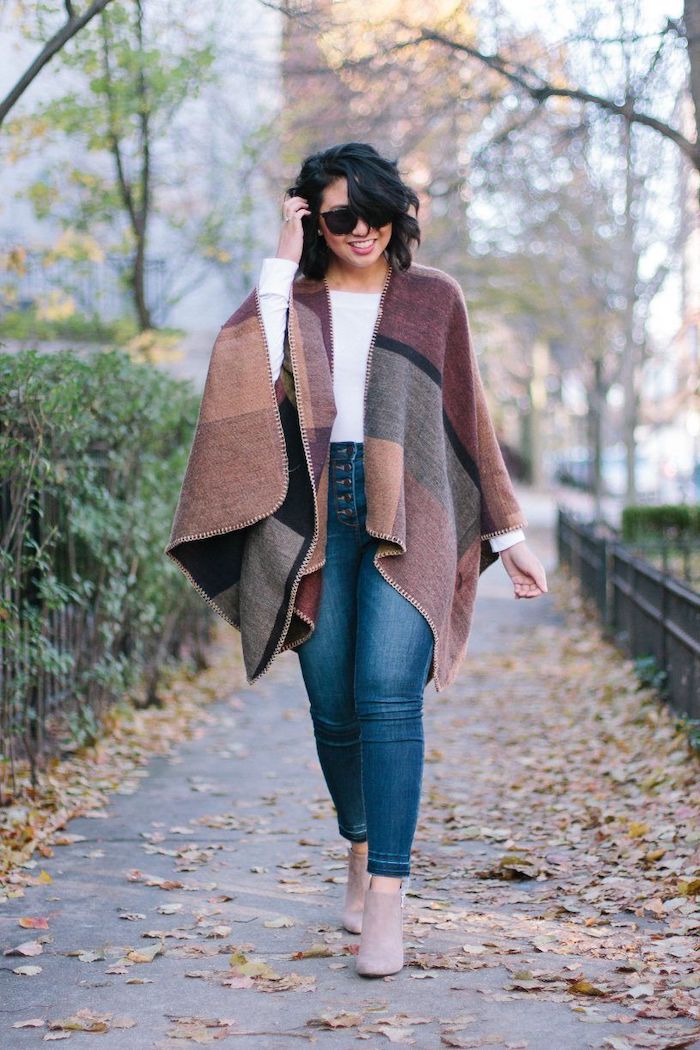 tendance automne hiver une femme en cape brun avec des jeans blues et des bottes beiges