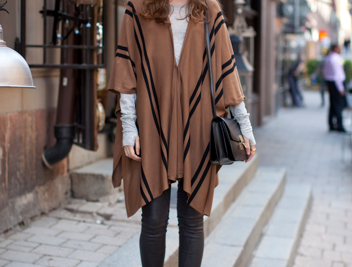 une femme avec une cape beige en raies noires et pantalon slim en cuir tendance automne hiver.jpg