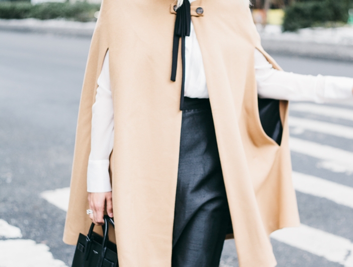 une femme avec une cape d hiver beige decore d un ruban et jupe noire en cuir