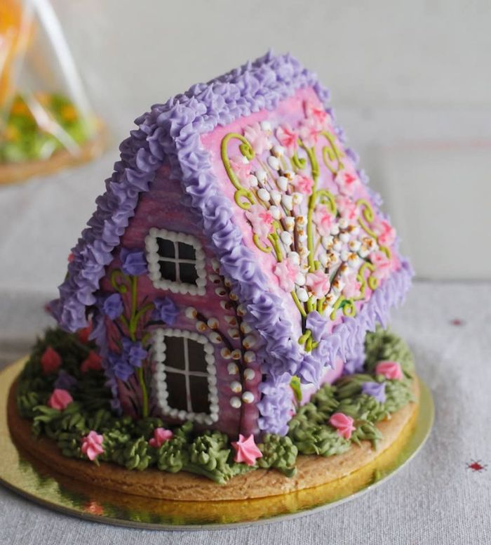 une maison en pain d épices decorée de fleurs en creme violet et rose idee de dessert de noel