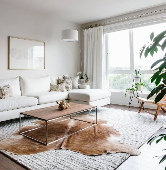 ambiance cosydans un salon scandinave minimaliste aux murs et canapé blancs table basse bois sur tapis blanc parquet bois marron plantes vertes d intérieur