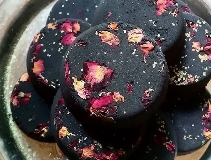 boules de bain maison en noir avec des petales de rose ranges sur une assiette argentine